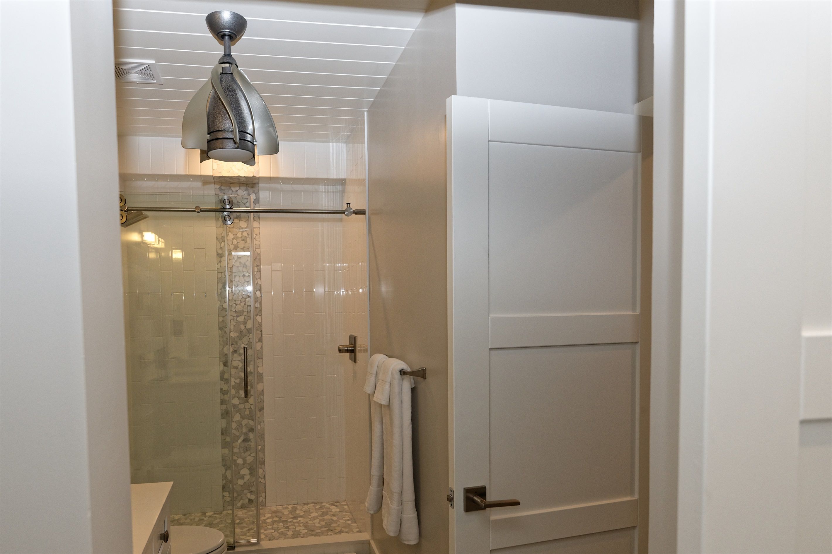 A bathroom with a shower, toilet, and a towel rack.