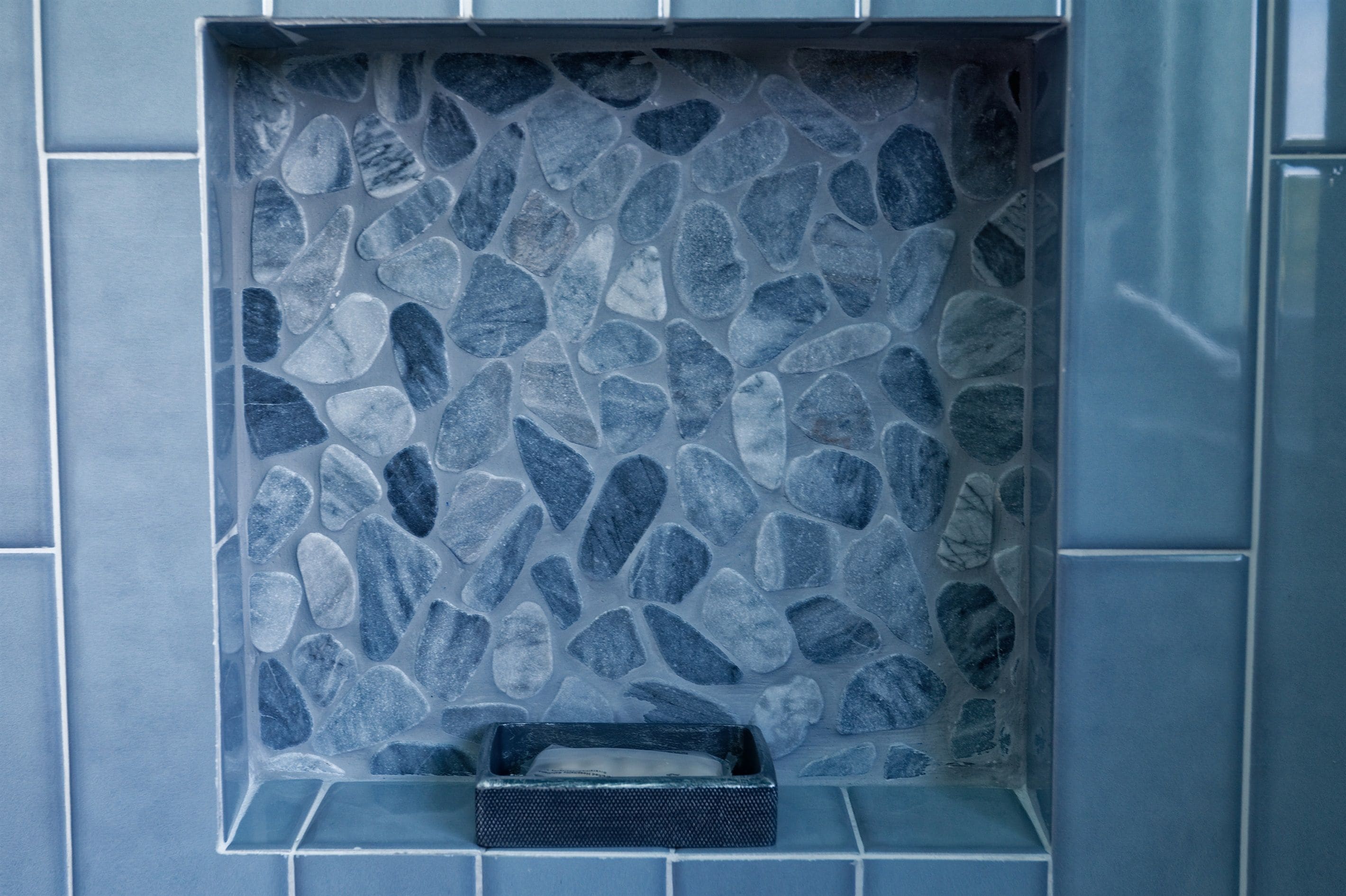 A bathroom with a stone mosaic wall, a built-in sink, and a towel rack.