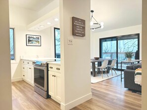 A modern kitchen with white cabinets and stainless steel appliances, a dining area with a large window, and a cozy living room with a gray sofa. - Walk to the Lifts! Park City 3BR Condo w/ Garage (Park City)