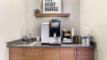 A modern kitchen with a coffee machine, a framed quote on the wall, and a coffee maker on the counter.