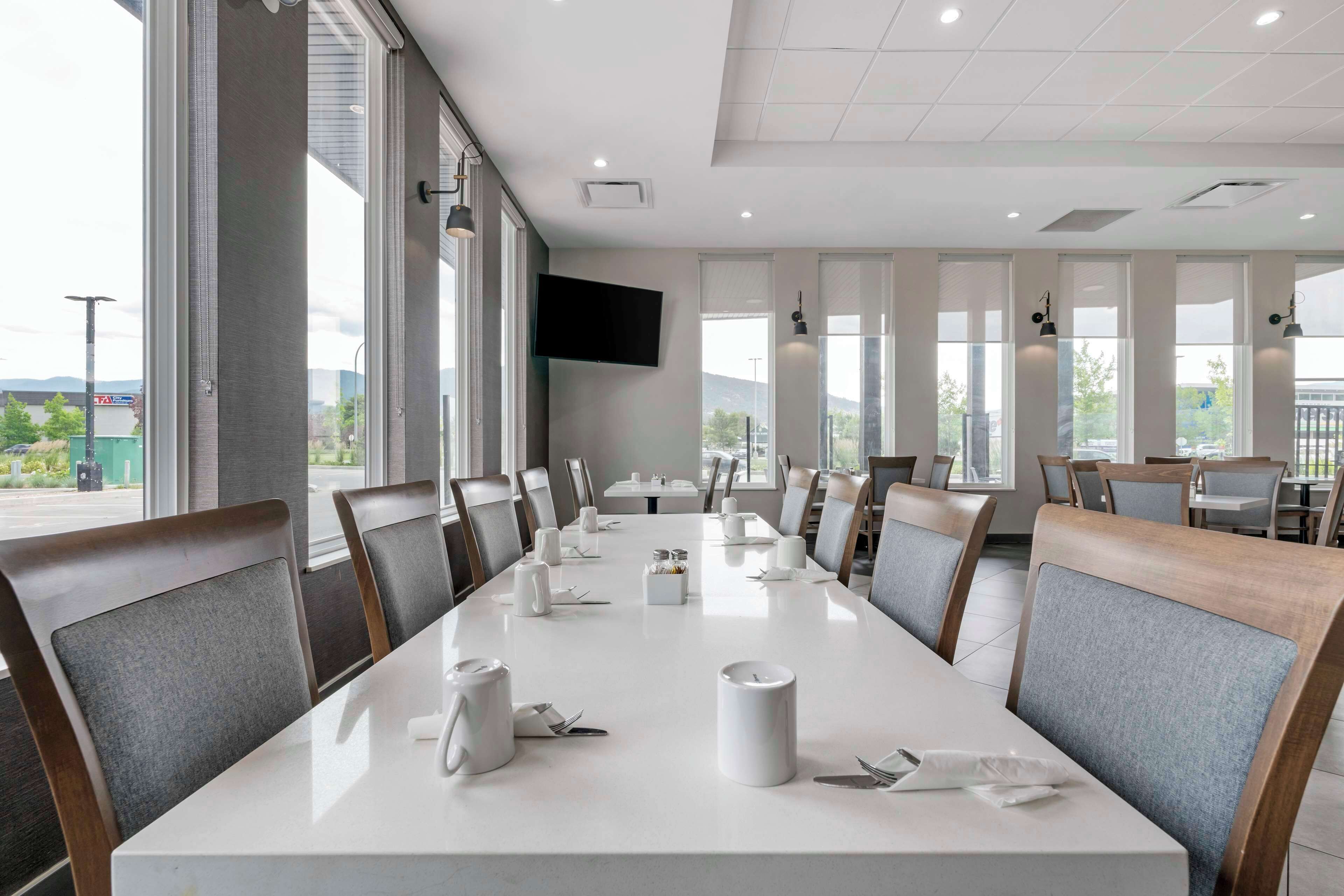 Un salón de conferencias con una larga mesa lista para reuniones, amplias ventanas con vistas y modernas lámparas.