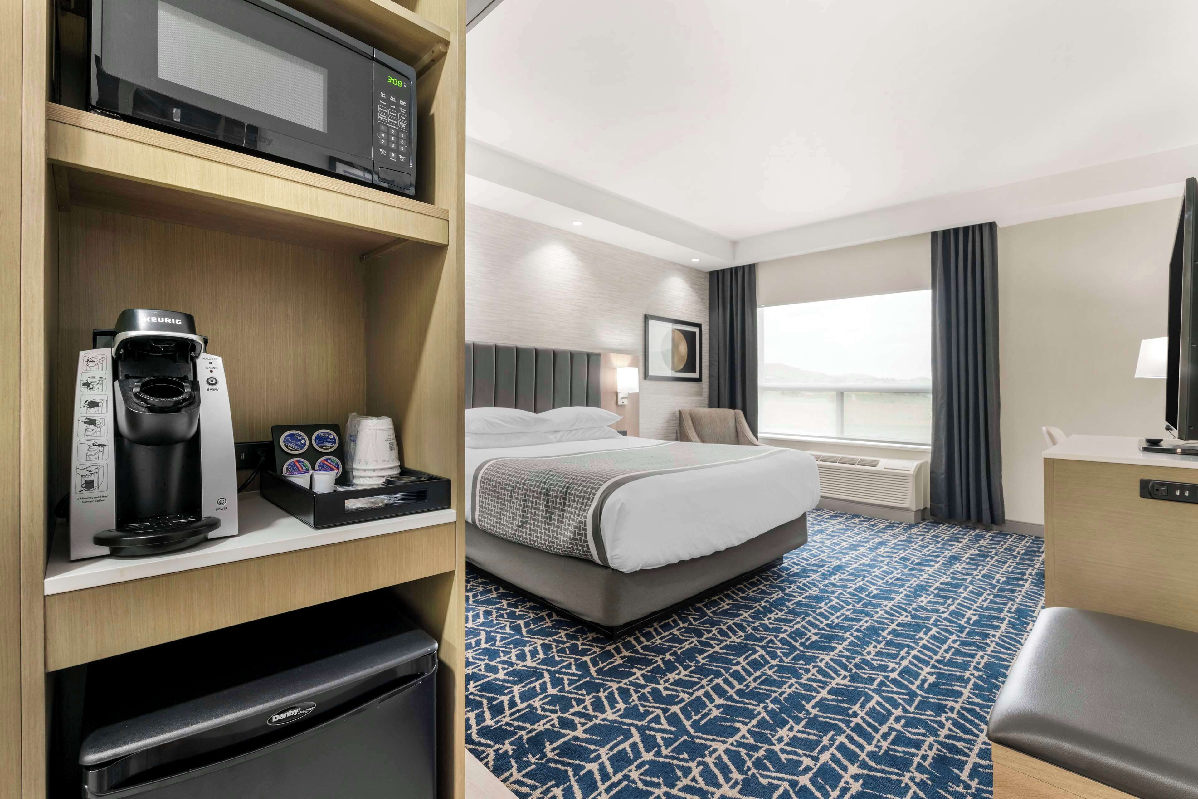 Habitación de hotel con cama, máquina de café, microondas y televisión.