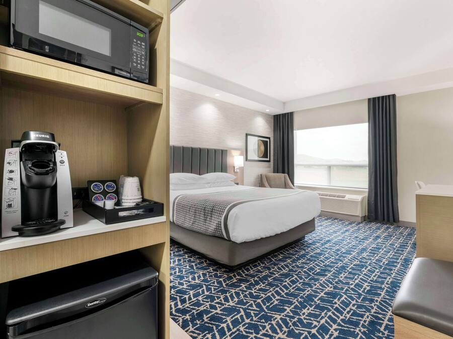 Habitación de hotel con cama, máquina de café, microondas y televisión.