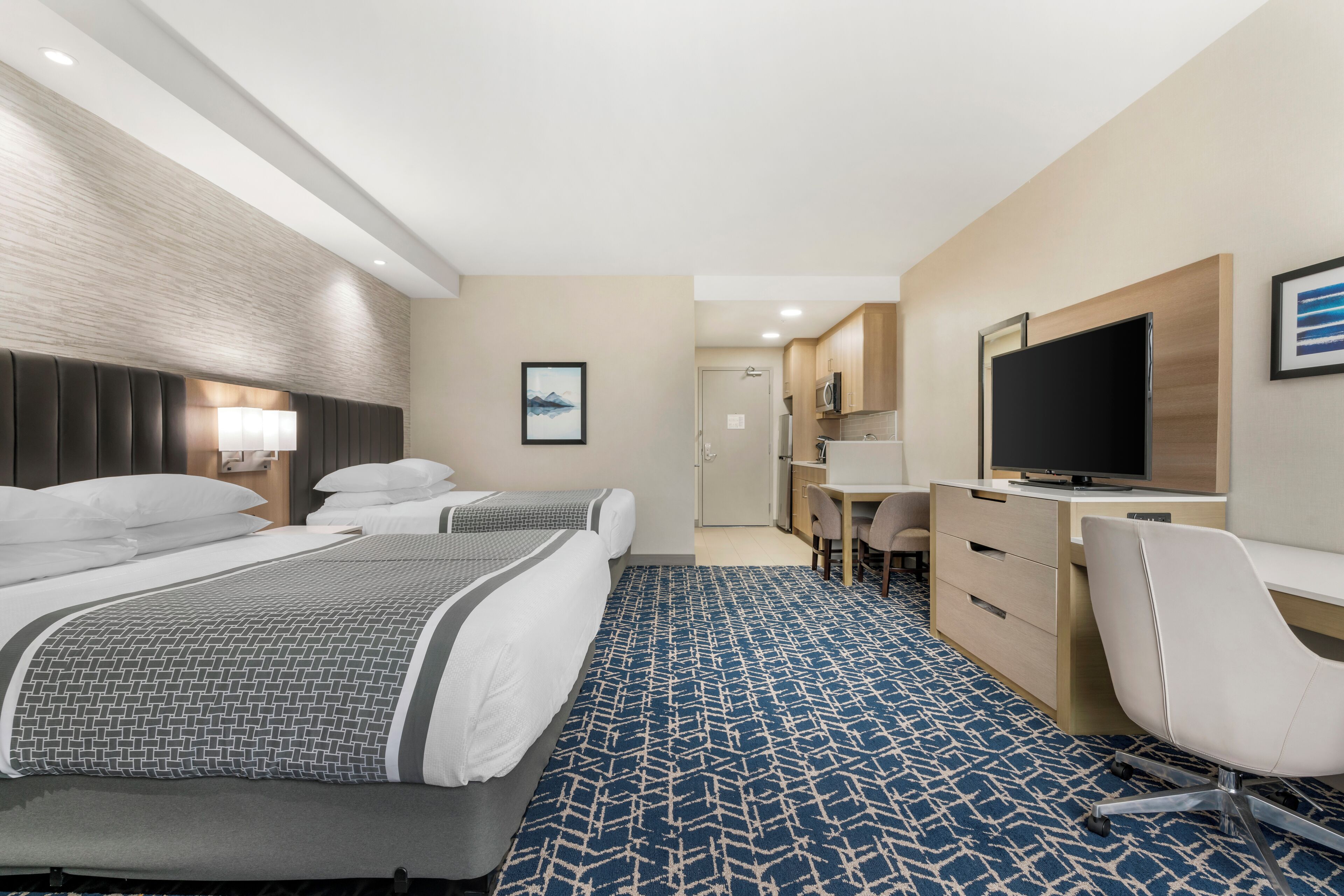 Une chambre d’hôtel avec deux lits, un bureau, une télévision et une salle de bain.