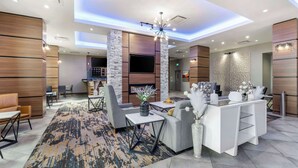 A modern hotel lobby with a central seating area, a reception desk, and a TV mounted on a stone pillar. - Best Western Premier Route 97 Vernon (Vernon)