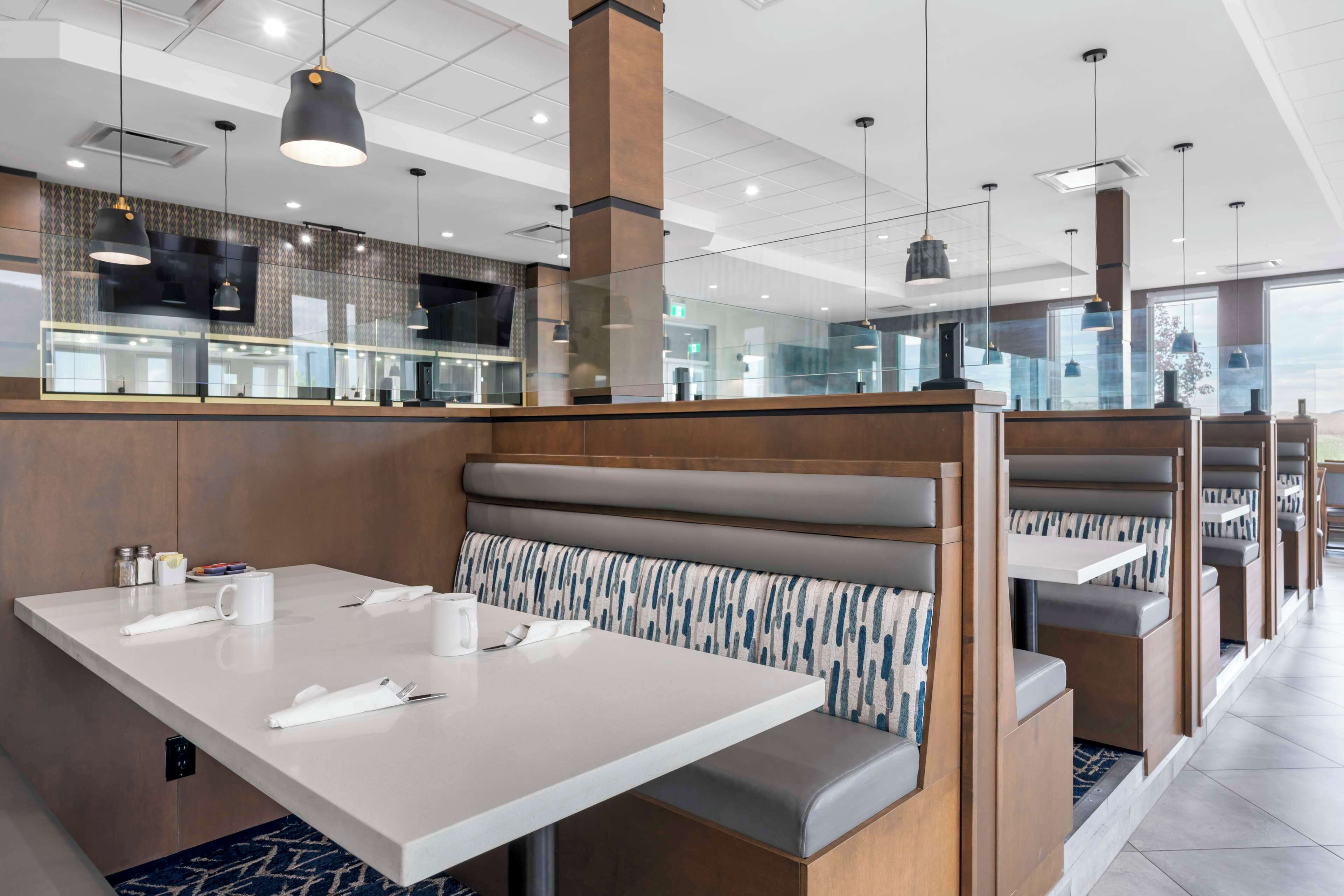 Ein modernes Restaurant mit einer langen Theke, gepolsterten Sitzecken und Pendelleuchten.