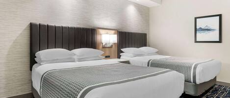 Habitación de hotel con dos camas, una mesita de noche, una lámpara y un cuadro en la pared.