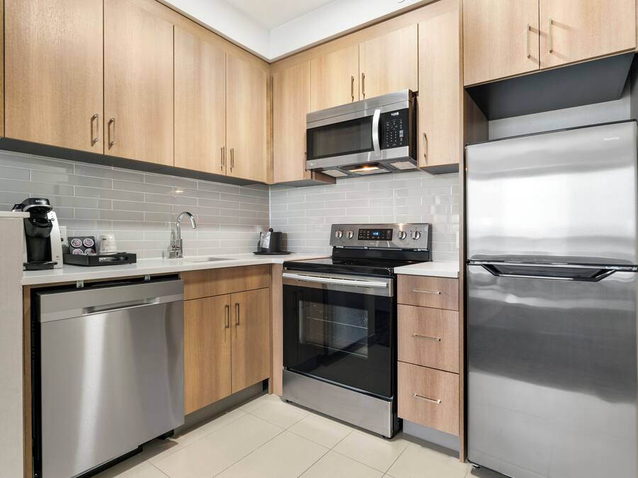 Een moderne keuken met roestvrijstalen apparatuur, houten kastjes en een betegelde achterwand.