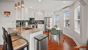 Una cocina moderna con armarios blancos, un refrigerador de acero inoxidable y una isla de mármol.