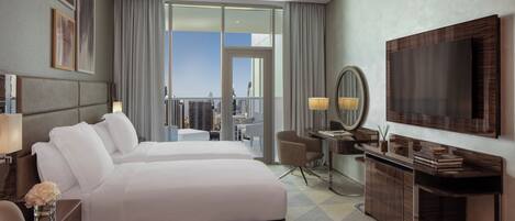 Habitación de hotel con cama, escritorio, silla, televisor y vista a la ciudad.