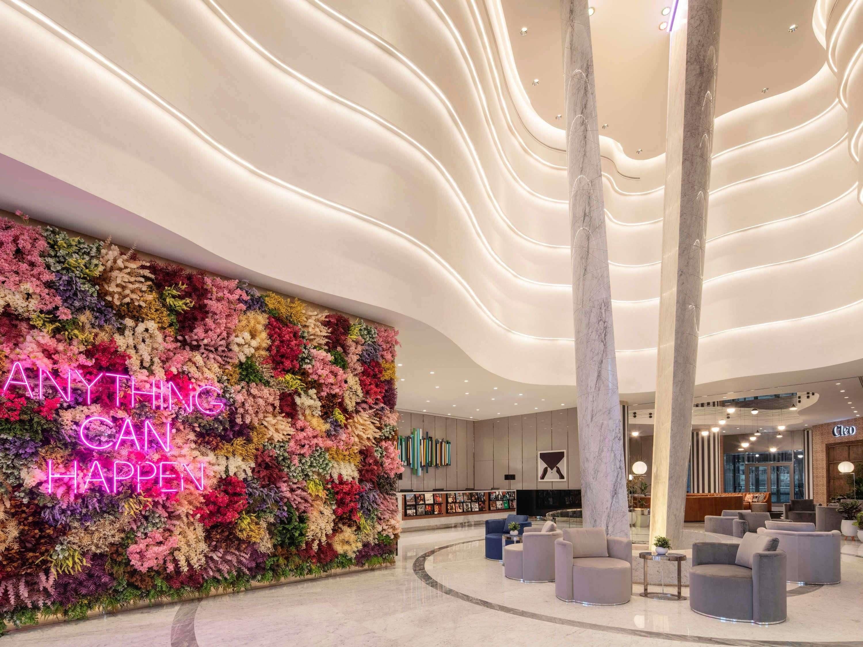 Un vestíbulo con una pared floral, una columna de mármol y zonas de estar.