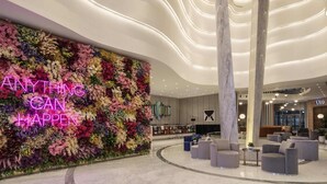 A modern lobby with a floral wall, a marble column, and a seating area. - Hyde Hotel Dubai (Dubai)