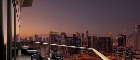 A balcony with a city view, a table with a glass, and wicker chairs.