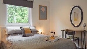 A neatly arranged bedroom with a bed, bedside table, and a small desk with a chair. - 1 bedroom accommodation in St Andrews (St Andrews)