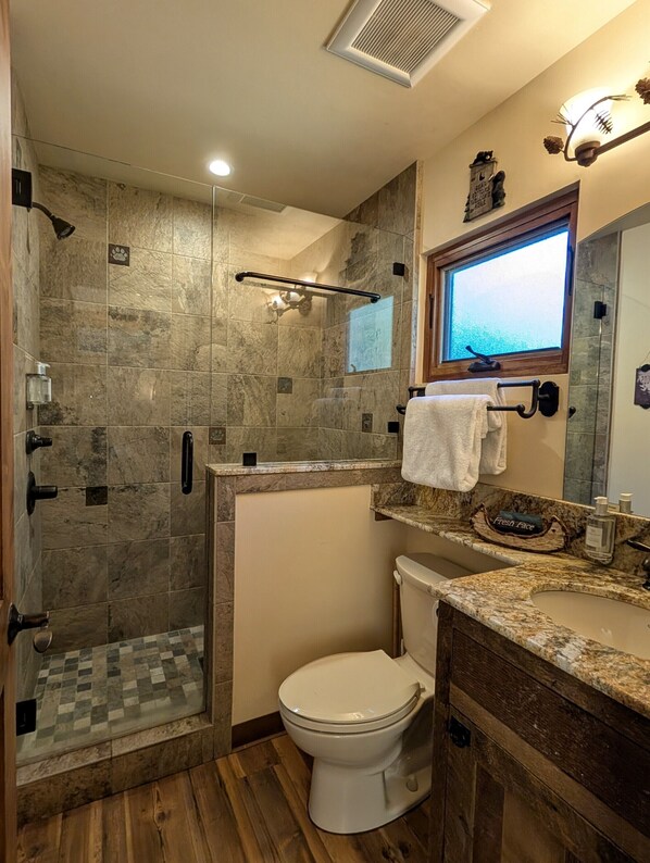 Un baño con ducha, inodoro y tocador.