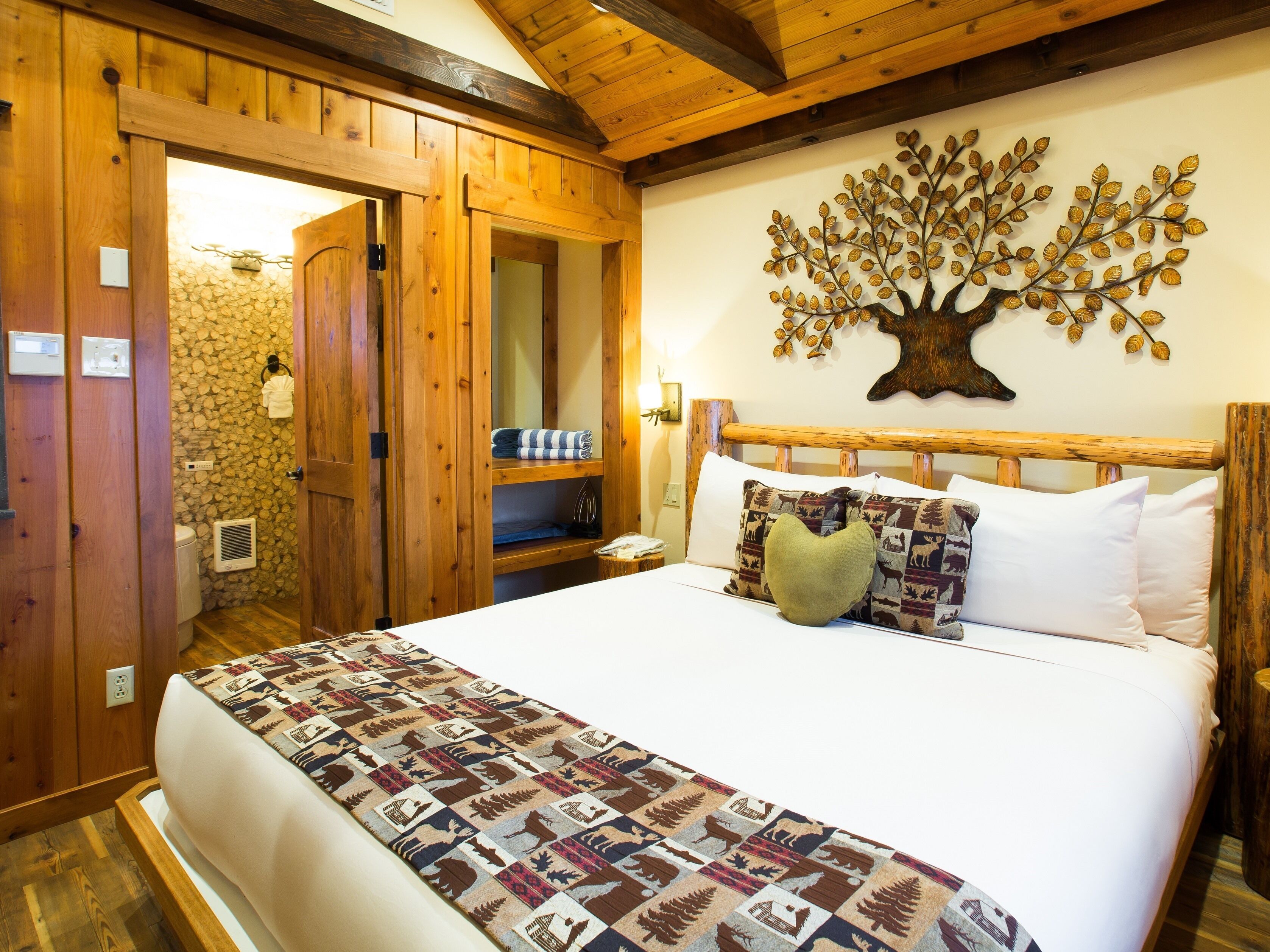 Um quarto de madeira com uma cama, uma decoração de árvore fixada na parede e uma parede de pedra.
