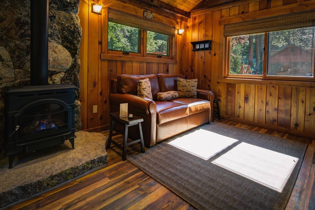 Ein gemütliches Blockhauss-Interieur mit Ledersofa, Kamin und Holzwänden.