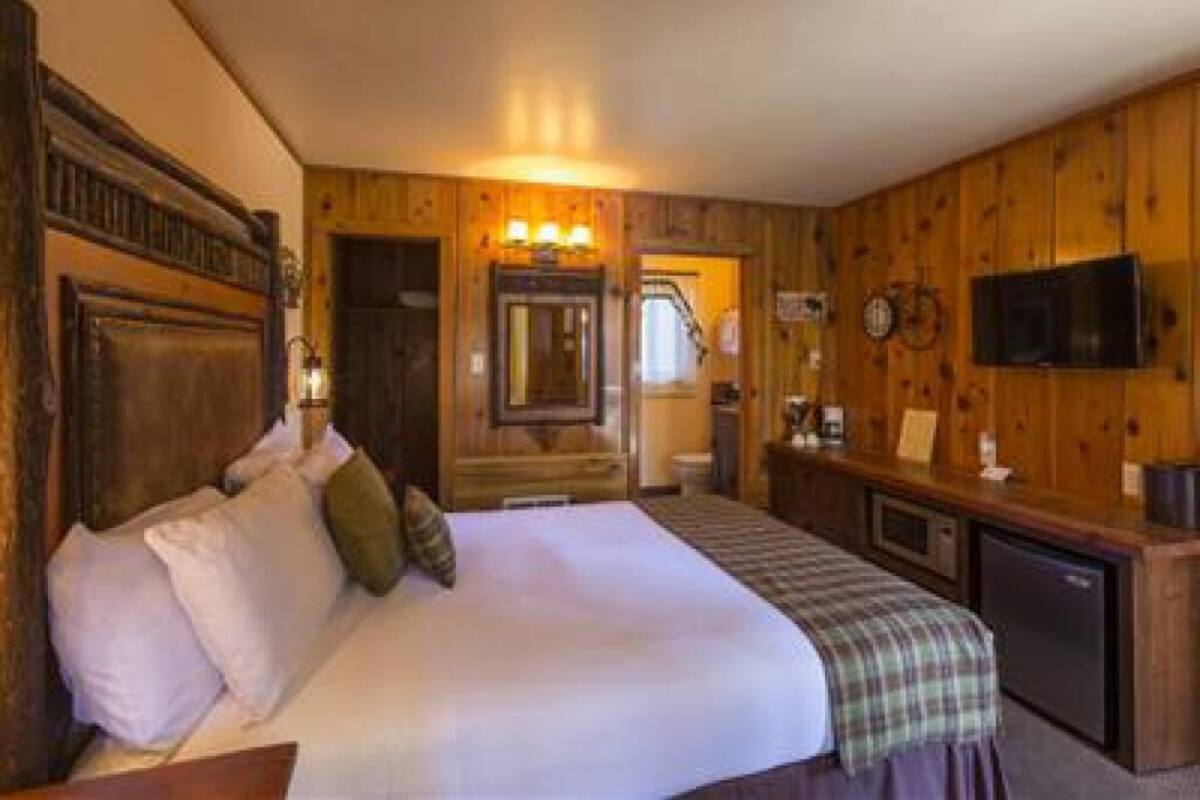 Ein Zimmer mit Holzwänden, einem Bett, einem Schreibtisch und einem Fernseher.