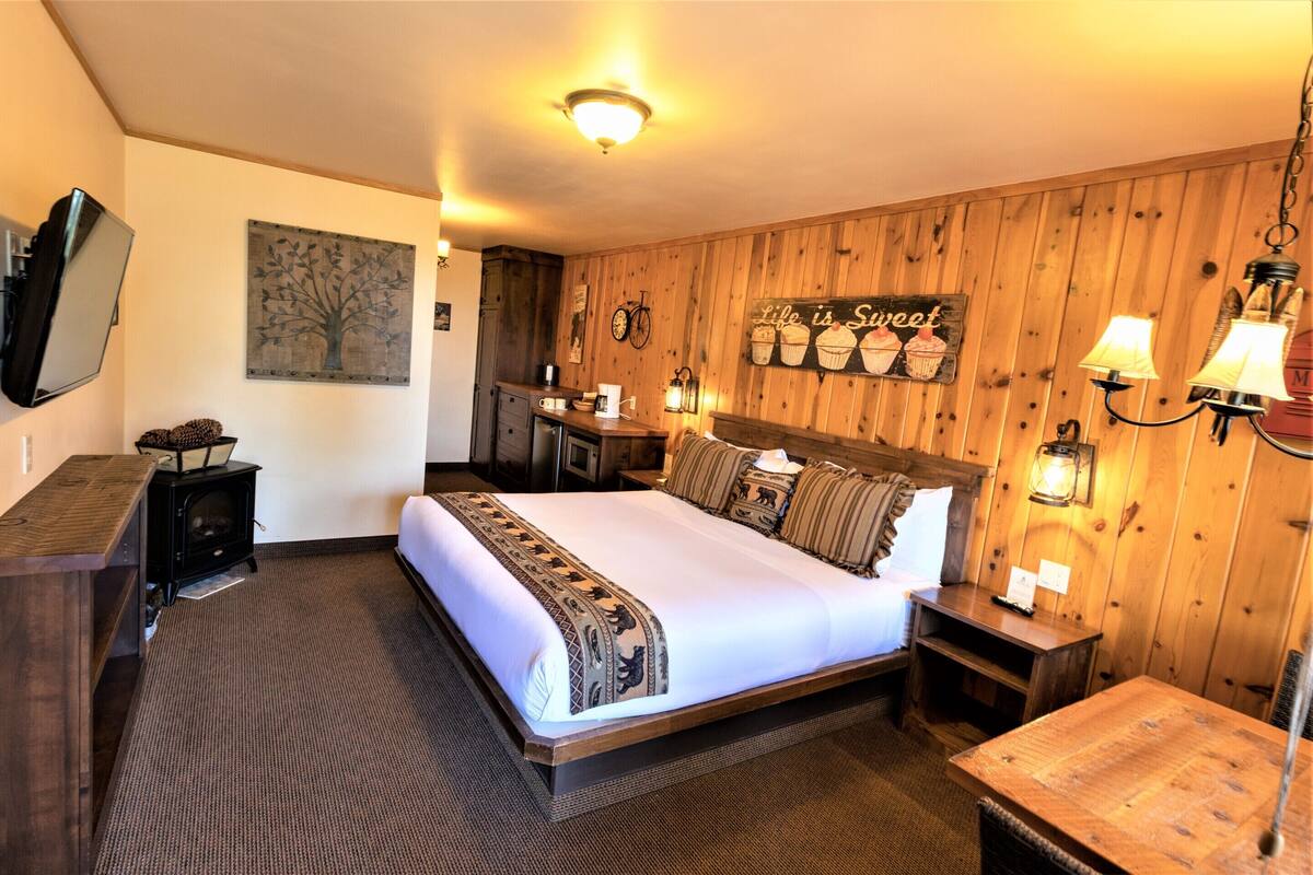 Ein gemütliches Hotelzimmer mit einem großen Bett, Holzwänden, einem an der Wand befestigten Fernseher und einem Schild mit der Aufschrift 'Life is Sweet'.