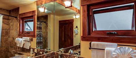 A bathroom with a marble sink, a large mirror, and wooden accents.