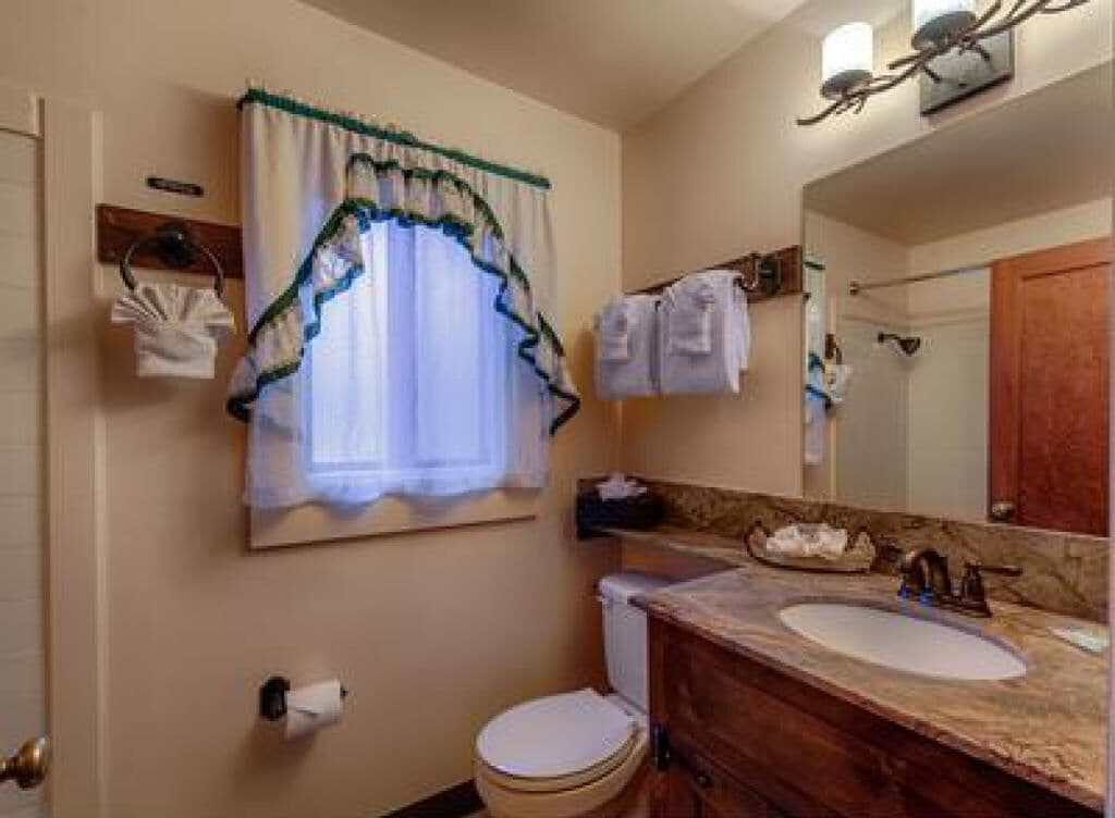 A bathroom with a toilet, sink, and mirror.