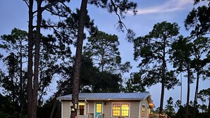 A single-story house with a front porch, a small deck, and a well-maintained lawn. - Marsh Beauty (Alligator Point)