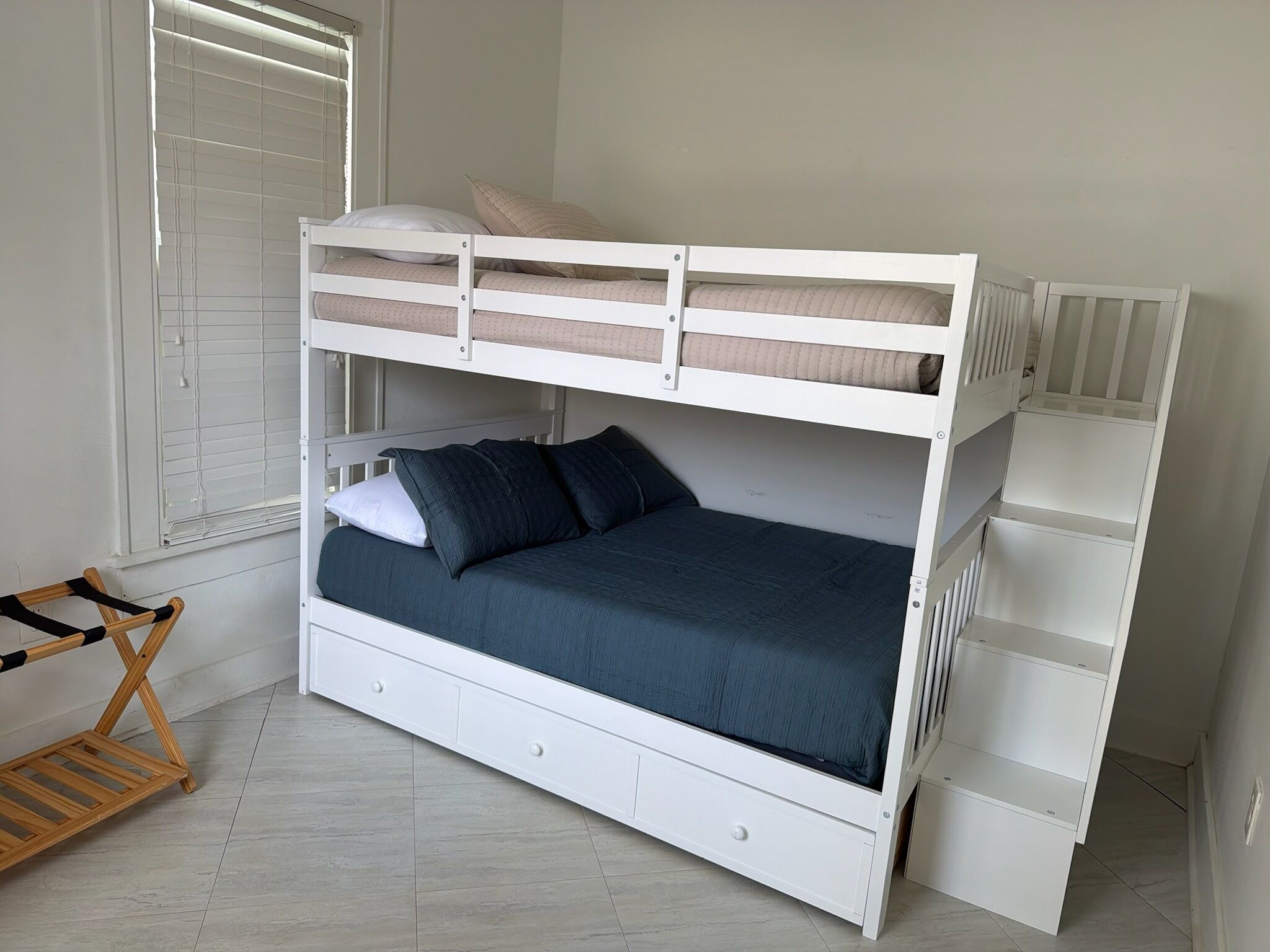 Una cama litera con un cajón de almacenamiento, una silla de madera y un radiador.