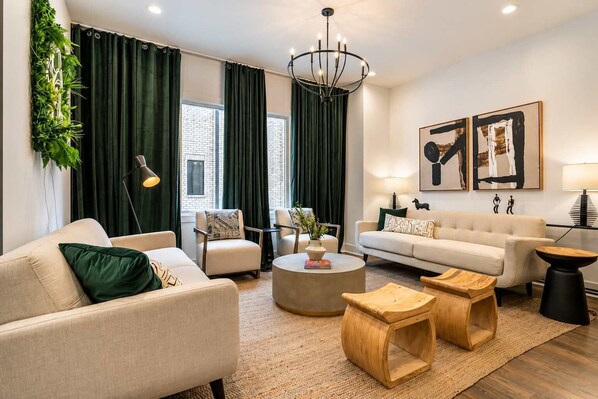 A modern living room with a sofa, armchairs, a coffee table, and a chandelier.