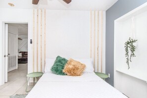 Relax in a serene bedroom with a bed, side table, and a hanging plant.