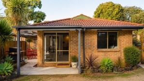 A single-story brick house with a tiled roof, a covered patio, and a visible garage. - Golfside Getaway by Ready Set Stay - Neat bungalow,WIFI,linen & towels included (Rosebud)