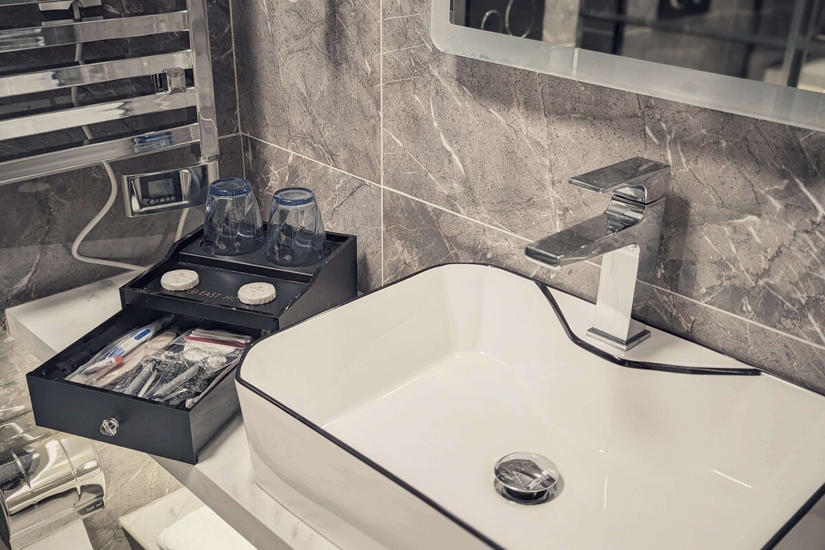 Une salle de bain moderne avec un lavabo blanc, un porte-savon noir et un miroir au-dessus du lavabo.
