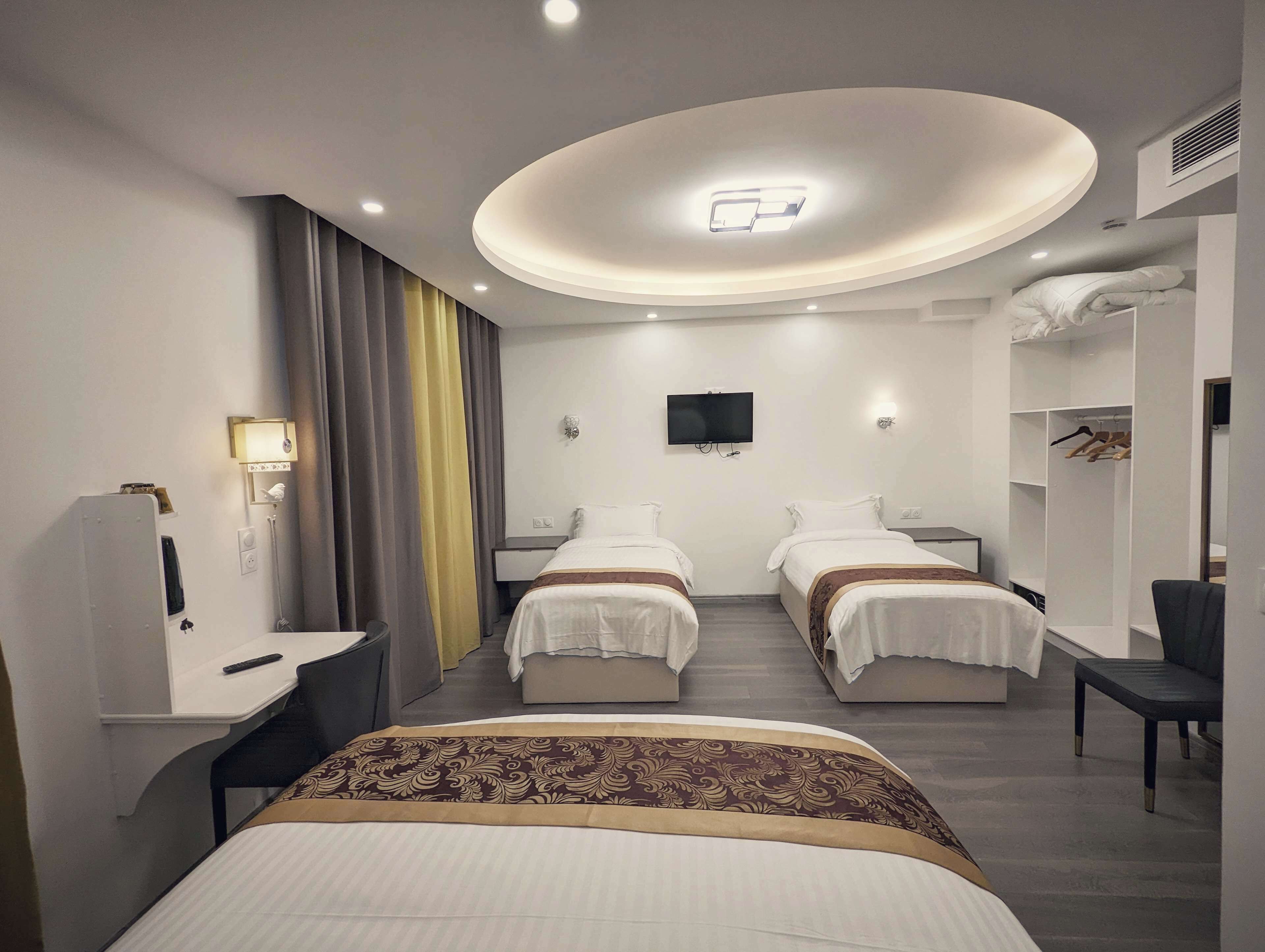 A modern hotel room with two beds, a desk, a TV, and a wardrobe.