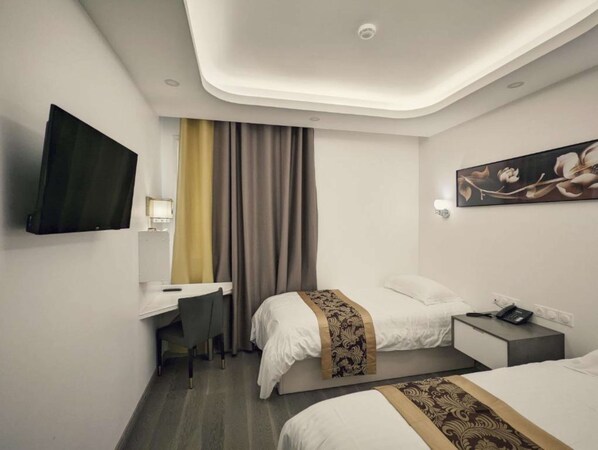 Habitación de hotel con cama, escritorio, silla, televisor y un cuadro en la pared.