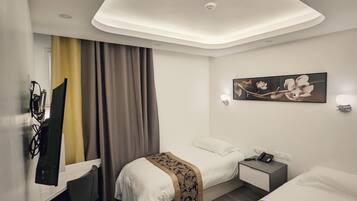 A hotel room with two beds, a desk, a chair, a desk lamp, a telephone, and a painting on the wall.