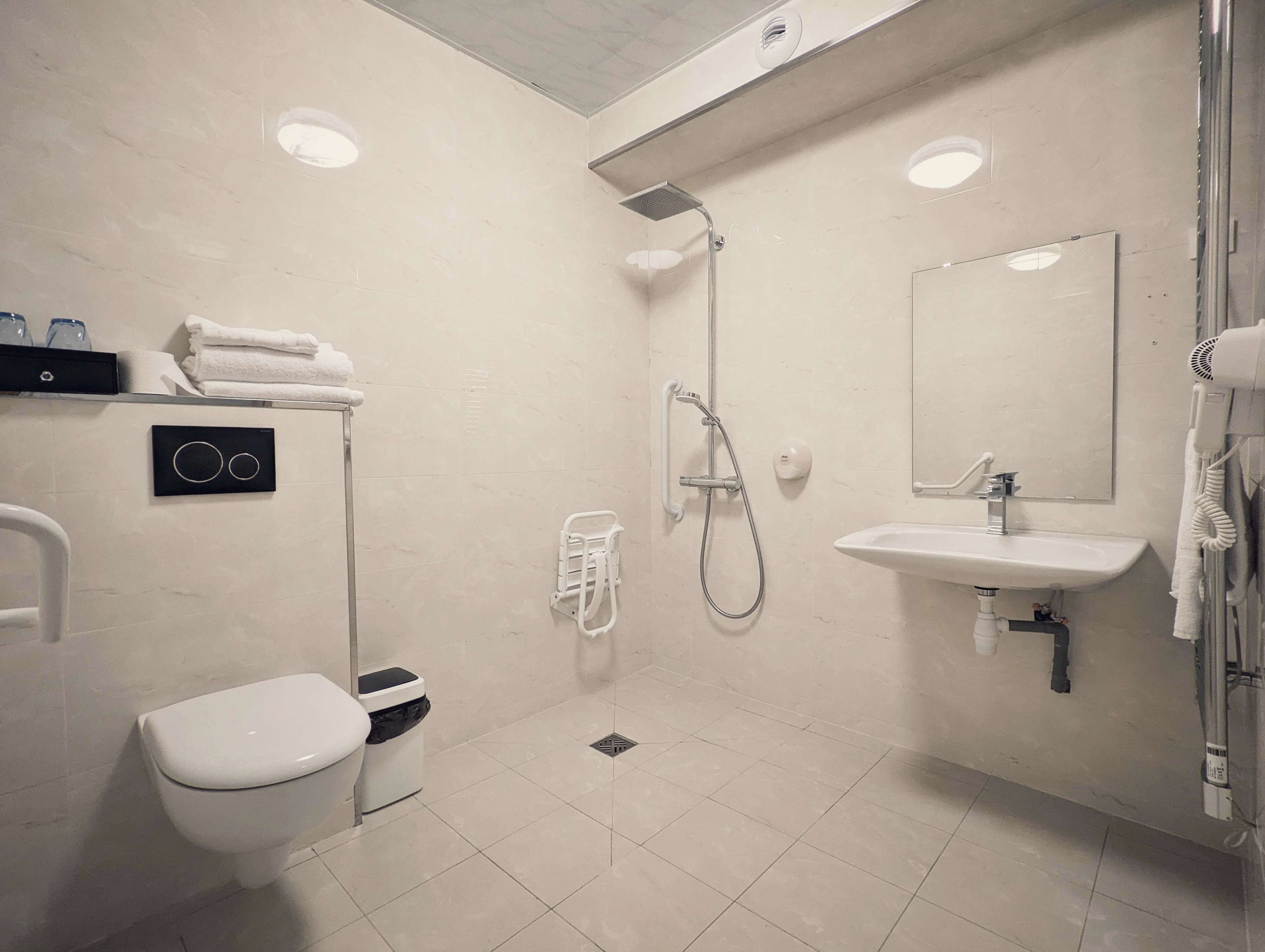 A modern bathroom with a toilet, bidet, shower, sink, and a towel rack.