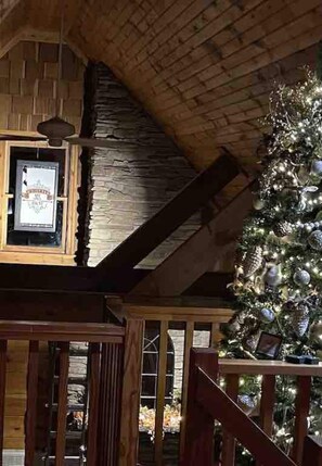 Ein rustikales Holzhaus mit einem Steinsschornstein, einem geschmückten Weihnachtsbaum und einem gerahmten Schild an der Wand.