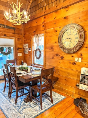 Enjoy meals in this charming dining area with a traditional table for four, a large wall clock, and warm wooden paneling.