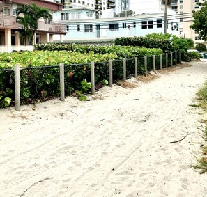 Residents stroll along a tranquil pathway to their homes with balconies and windows.