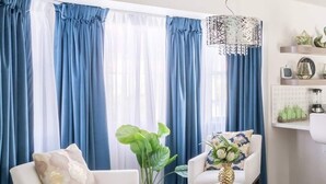 Una sala de estar moderna con un sofá blanco, un sillón más pequeño, una mesita de centro y una alfombra mullida.