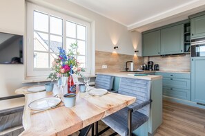 Une cuisine moderne avec un coin repas, comprenant une table en bois, des chaises bleues et un vase avec des fleurs.