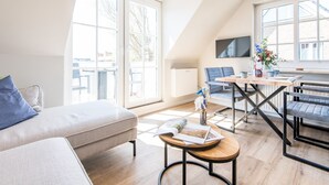 Een moderne woonkamer met een bank, een eettafel met stoelen en een keukenhoek.
