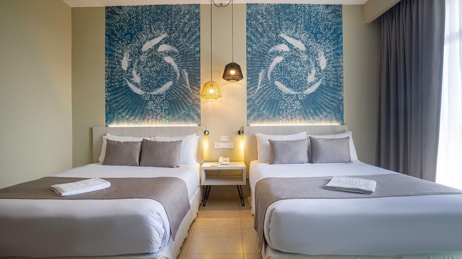 A hotel room with two beds, a nightstand with a phone, and a wall with a blue abstract design.