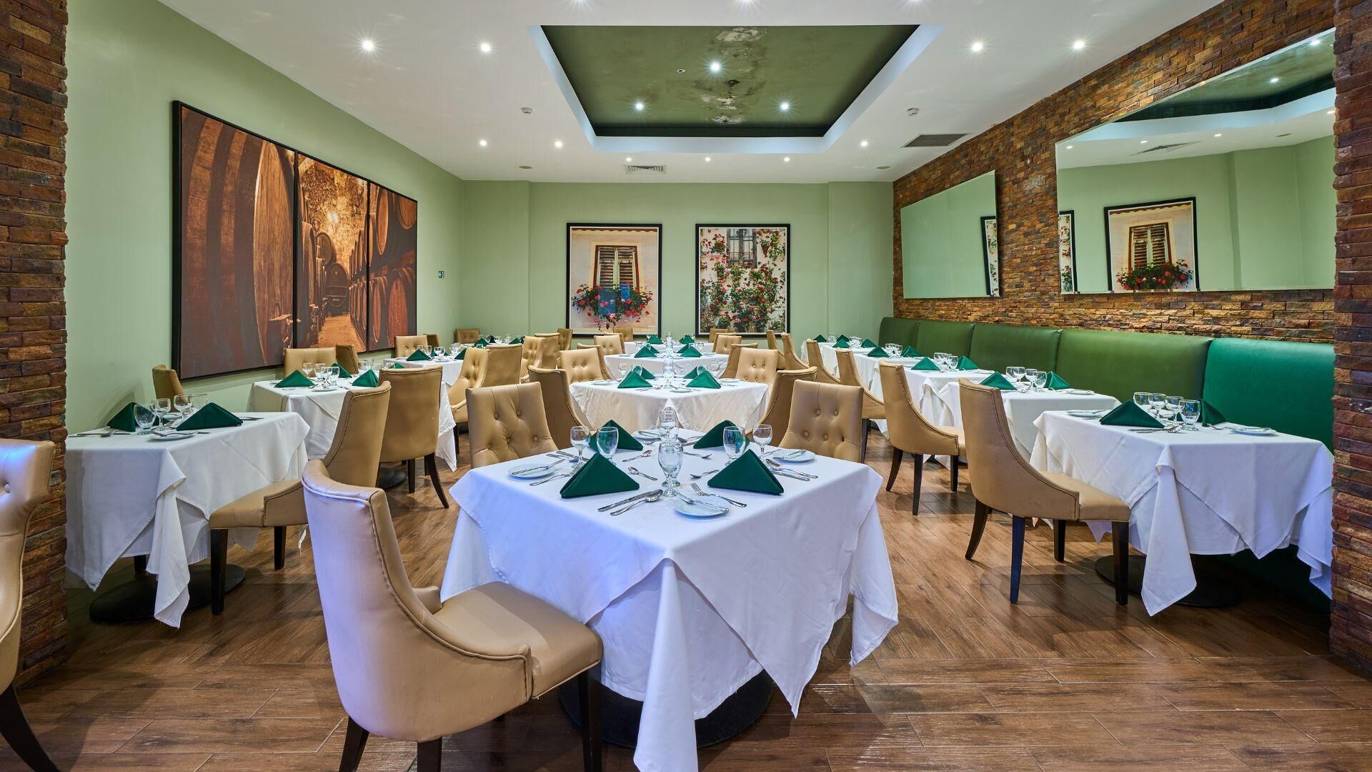Un restaurant avec des tables rondes, des serviettes vertes et un mur en briques.