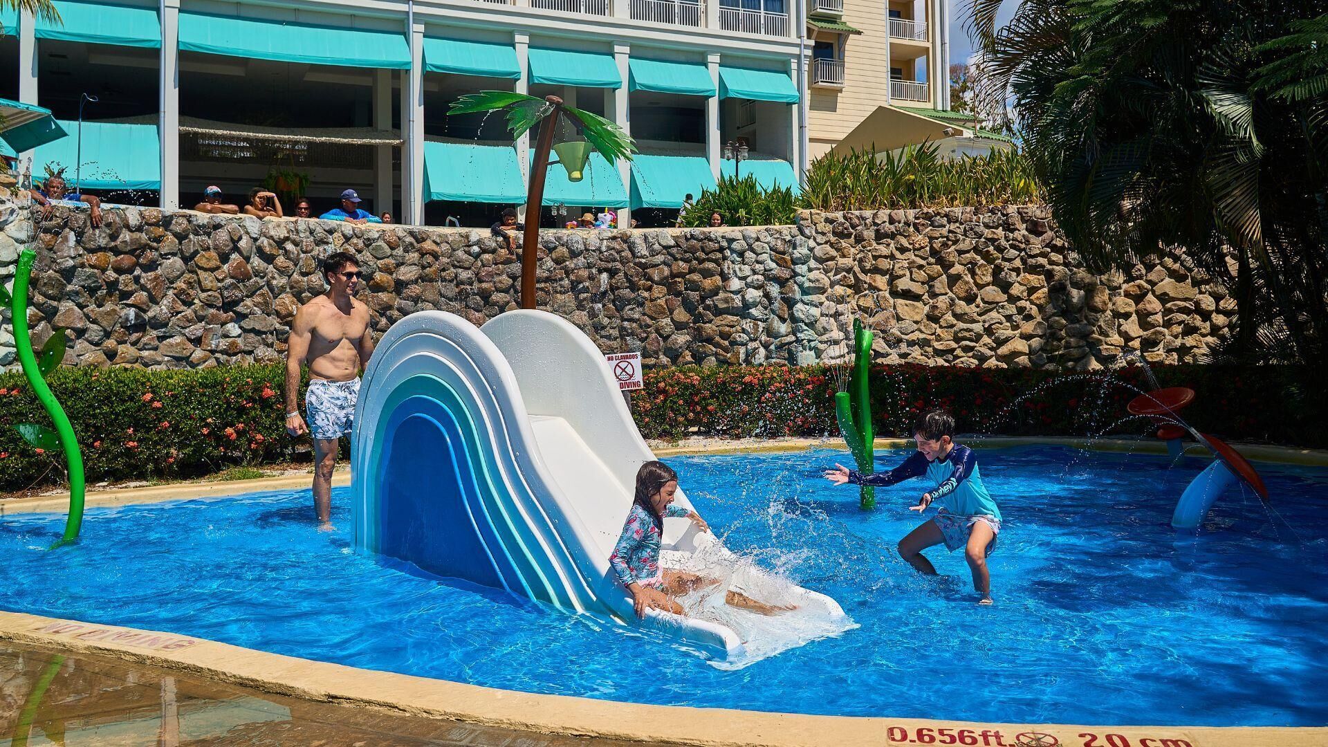 A water park with a large slide, a pool, and a stone wall.