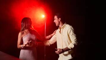 A couple dancing in a dimly lit room with a red light in the background.