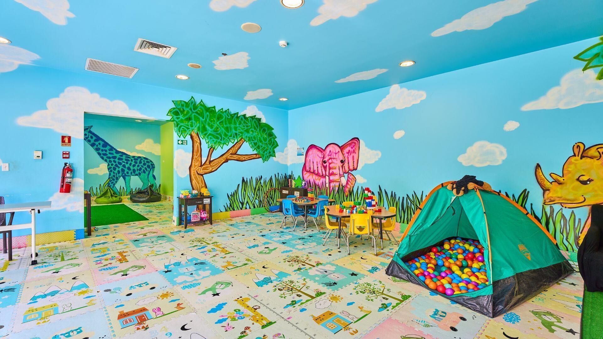 A children's playroom with colorful murals, a play area, and a tent.