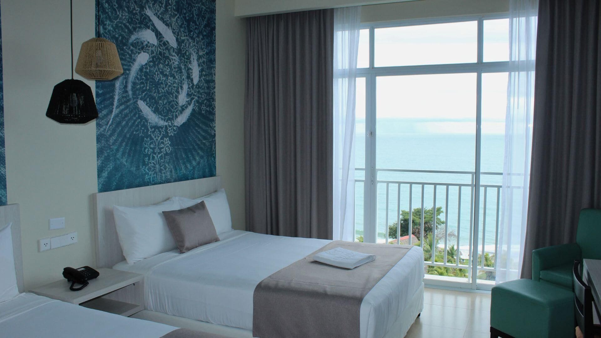Een hotelkamer met een groot bed, uitzicht op zee en een balkon.