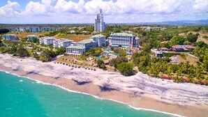 An aerial view of a coastal resort with multiple buildings, a beach, and a mountainous backdrop. - Gran Evenia Bijao - All Inclusive (Rio Hato)