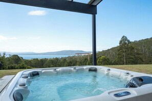 A hot tub with a clear view of the sea and hills in the background. - Ocean views, spacious & private, hot hub (Lower Snug)