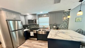 A modern kitchen with stainless steel appliances, a marble island, and pendant lighting.